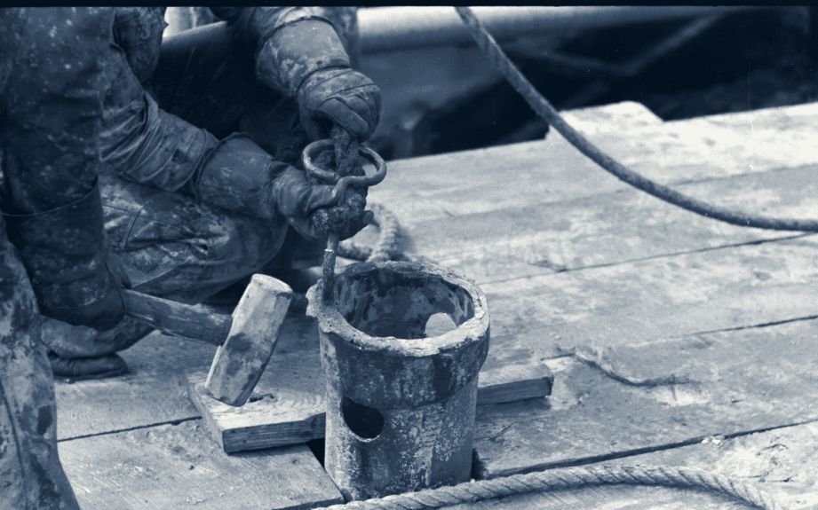 Threading the bailer on the drill floor - archival photograph. The craft passes hand to hand